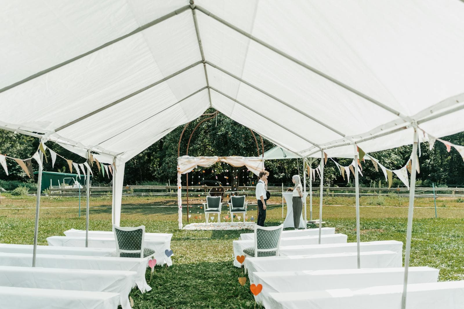An outdoor wedding ceremony setup under a white tent